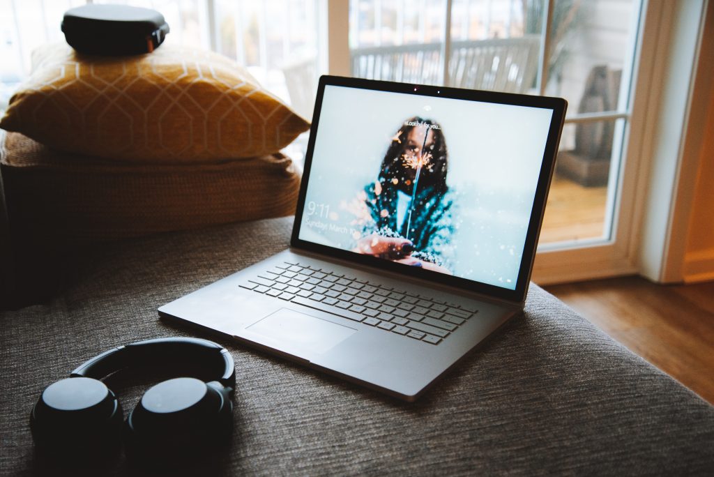 Laptop on a suface with pillow on the background