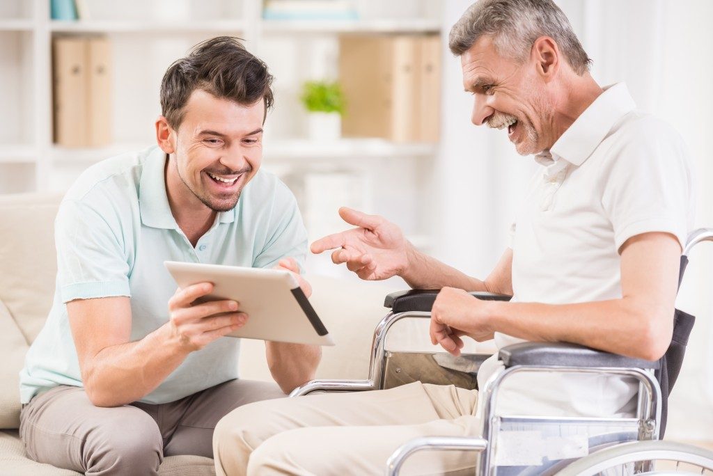 caregiver and old man holding a tablet